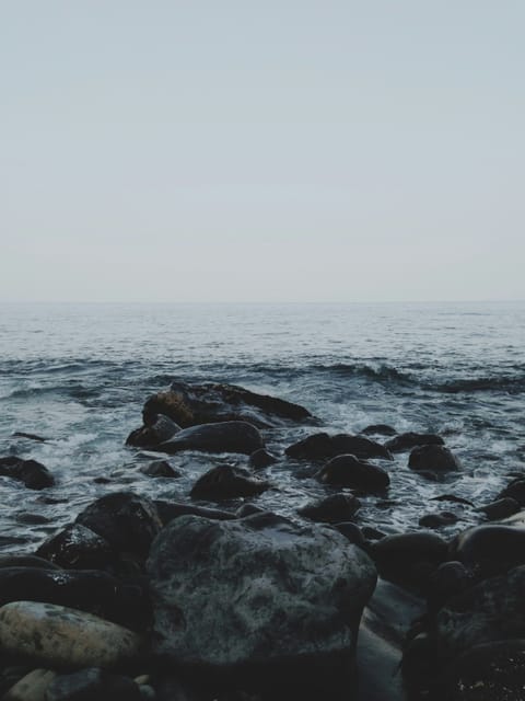 Steine im Meer mit Horizont. Diesiges Wetter.