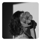 Eine Frau mit einer Blume vor dem Gesicht, Kurze haare, fröhliches Bild.